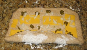 Form the dough into a rectangle and arrange the cheese, onions and jalapenos over the surface; roll up along the wide edge